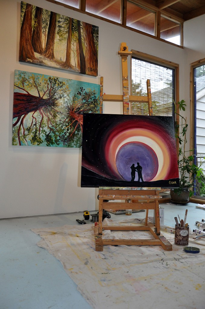 Paintings in Cedar Lee art studio. "Eclipse Love" on easel. Background: "Forest Nymph" (top), "Quest for Light" (bottom.)