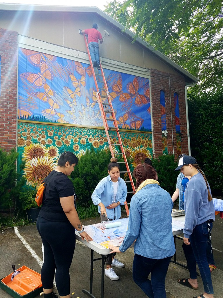 Cedar Lee assisting in installation of Hector Hernandez Monarca Mural in Portland, OR