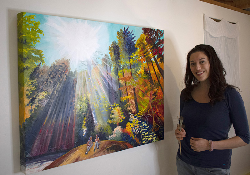 Artist Cedar Lee in the studio with colorful forest painting