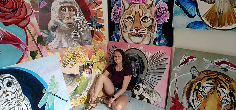 Artist Cedar Lee in her painting studio surrounded by large scale animal symbolism paintings