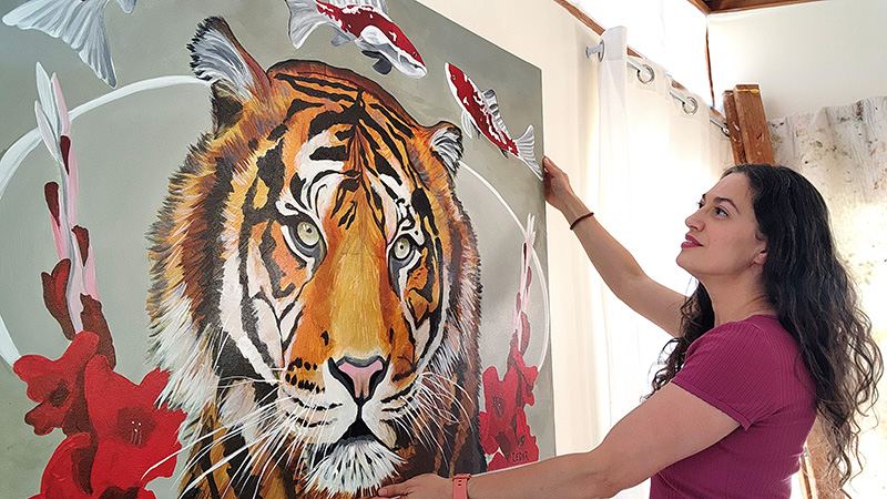 Artist Cedar Lee with painting of a tiger, titled The Hero