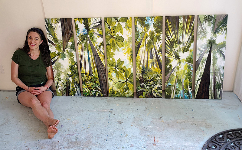 Artist Cedar Lee with green forest paintings